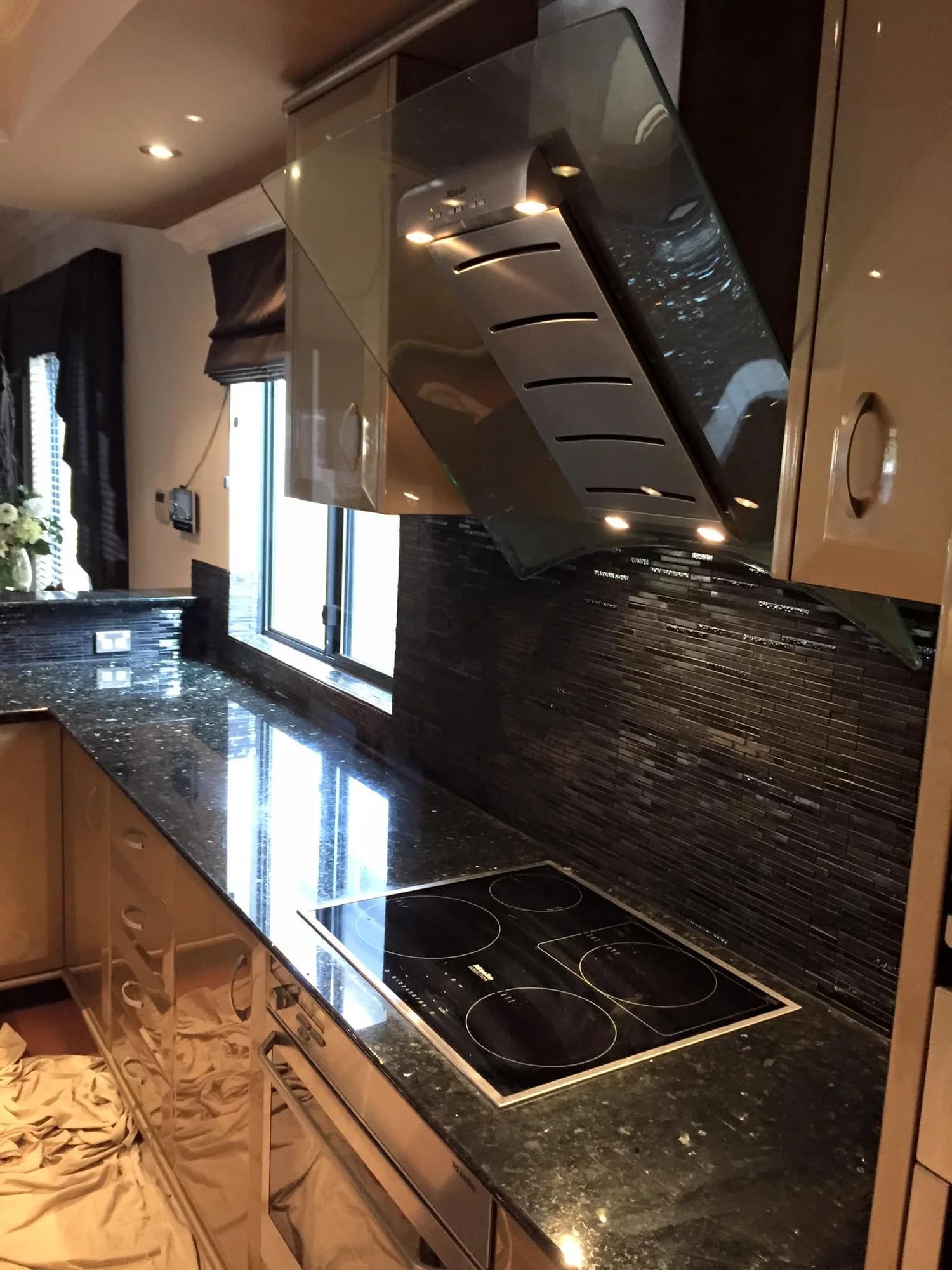 Commercial kitchen fit-out with black stone benchtops and glass mosaic splashback